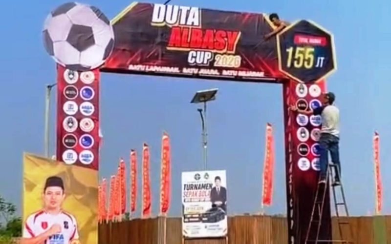 PERSIAPAN TURNAMEN: Sejumlah panitia sedang menyelesaikan pemasangan gapura megah untuk menyambut ajang sepak bola 'Duta Albasy Cup 2026'. Turnamen bergengsi ini menawarkan total hadiah fantastis sebesar Rp 155 Juta dan diprediksi akan menjadi sorotan utama pencinta bola di wilayah tersebut.